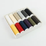 In einer weißen Schachtel befinden sich zwölf Spulen ACKERMANN® Universal Nähgarn „Farben-mix“ (12 × 200 m) in Stärke 120 mit verschiedenen Farben wie Gelb, Rot, Violett, Blau, Schwarz, Grau, Beige, Grün und Weiß. Die hochwertigen Polyesterfäden sind ordentlich in zwei Reihen vor einem weißen Hintergrund angeordnet.