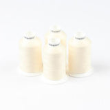 Vier Spulen ACKERMANN® Bauschgarn Nähgarn der Stärke 120 in der Farbe 5209 Beige (jeweils 1.000 m) sind auf einer weißen Fläche quadratisch angeordnet, wobei das ACKERMANN®-Logo auf der Oberseite jeder Spule aufgedruckt ist.