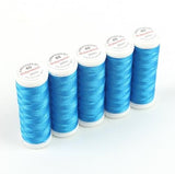 Fünf Spulen ACKERMANN® Stickgarn Stärke 40 (5 × 260 m, Farbe 2854 blau) sind aufrecht in einer Reihe auf weißem Hintergrund angeordnet – ein hochwertiges Garn, das sich ideal für Stickprojekte eignet.
