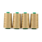 Vier Spulen beiges ACKERMANN® Universal-Nähgarn, Stärke 120 (Farbe 8065 bahamabeige) – jeweils mit grünen Ober- und Unterteilen – sind nebeneinander auf weißem Hintergrund angeordnet und heben das hochwertige, universell einsetzbare Polyester-Nähgarn mit einer Lauflänge von 5.000 m hervor.