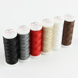Sechs Spulen ACKERMANN® Ackermann Nähgarn „Leather Mix“ 6 × 120 m, Stärke 60, in den Farben Schwarz, Grau, Rot, Beige, Weiß und Braun sind auf weißem Hintergrund in einer Reihe angeordnet.