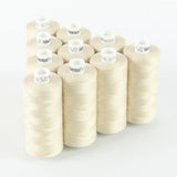 Zehn Spulen ACKERMANN® Universal-Nähgarn Stärke 120 (Farbe 7601: sehr helles Beige, 10 × 1.000 m) sind auf einer weißen Fläche in einer ordentlichen rechteckigen Anordnung angeordnet und aus einem leichten Winkel betrachtet.